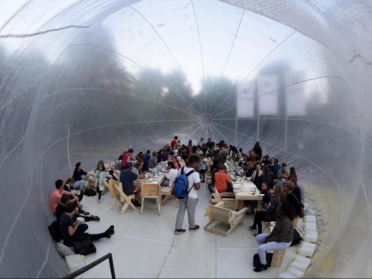 Menschen sitzen in dem Projekt "Kitchen Monument".