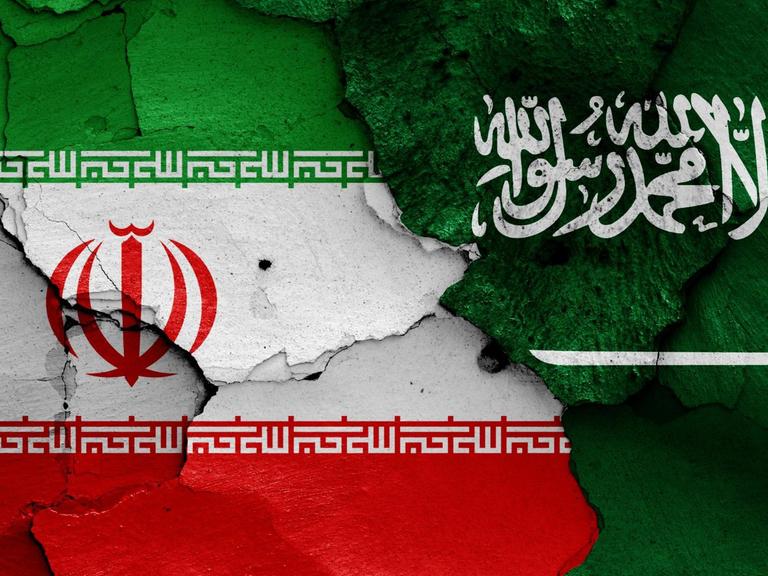 Die Flaggen von Iran und Saudi-Arabien sind auf eine bröckelnde Wand gemalt
