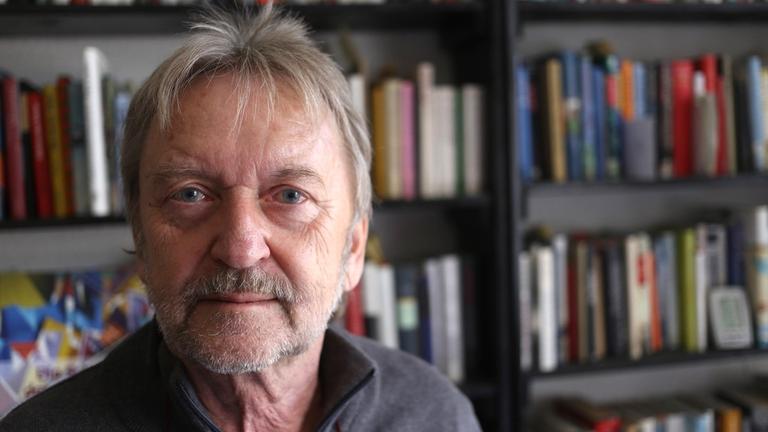 Michael "Salli" Sallmann, Liedermacher, Autor, DDR-Dissident. Ein älterer Mann steht vor einem Bücherregal und schaut in die Kamera. Michael "Salli" Sallmann, Liedermacher, Autor, DDR-Dissident. Ein älterer Mann steht vor einem Bücherregal und schaut in die Kamera.