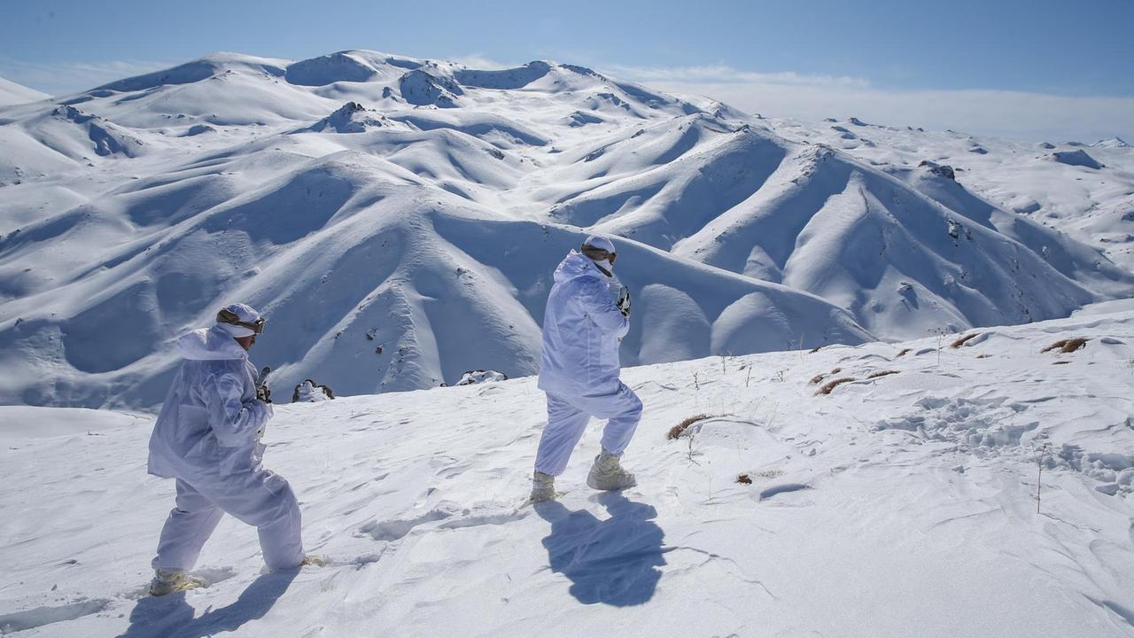 Militärisch unübersichtliches Gelände: Türkische Soldaten stapfen durch den Schnee, im Hintergrund ein Gebirge