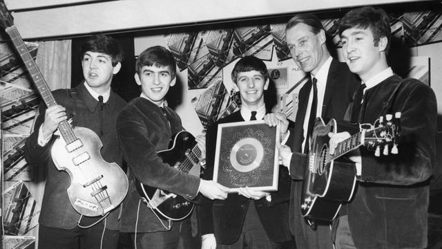 George Martin (2.v.r.) zusammen mit den Beatles bei der Übergabe einer Silbernen Schallplatte (für eine viertel Million verkaufte Alben) in London im Jahre 1963.
