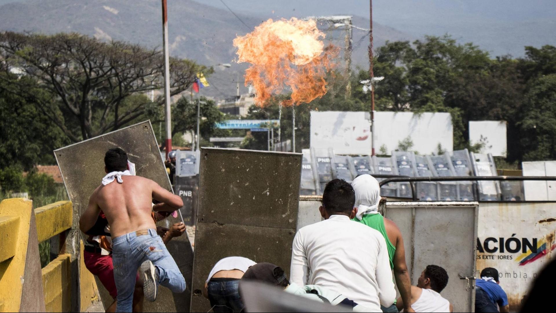Demonstranten schmeißen Steine an der Francisco de Paula Santander-Brücke, die an der Grenze zwischen Venezuela und Kolumbien Demonstranten schmeißen Steine an der Francisco de Paula Santander-Brücke, die an der Grenze zwischen Venezuela und Kolumbien