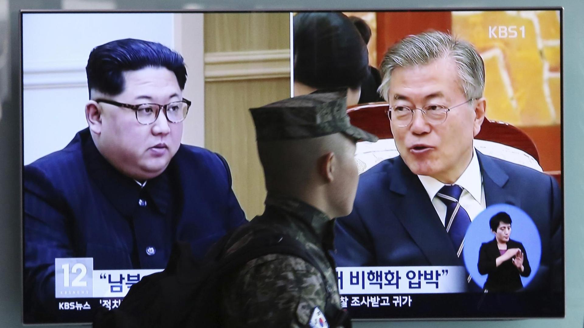 Ein südkoreanischer Marinesoldat geht an einem Fernseh-Bildschirm vorbei, der während einer Nachrichtensendung Bilder von Nordkoreas Machthaber Kim Jong Un und Südkoras Präsident Moon Jae In zeigt. Ein südkoreanischer Marinesoldat geht an einem Fernseh-Bildschirm vorbei, der während einer Nachrichtensendung Bilder von Nordkoreas Machthaber Kim Jong Un und Südkoras Präsident Moon Jae In zeigt.