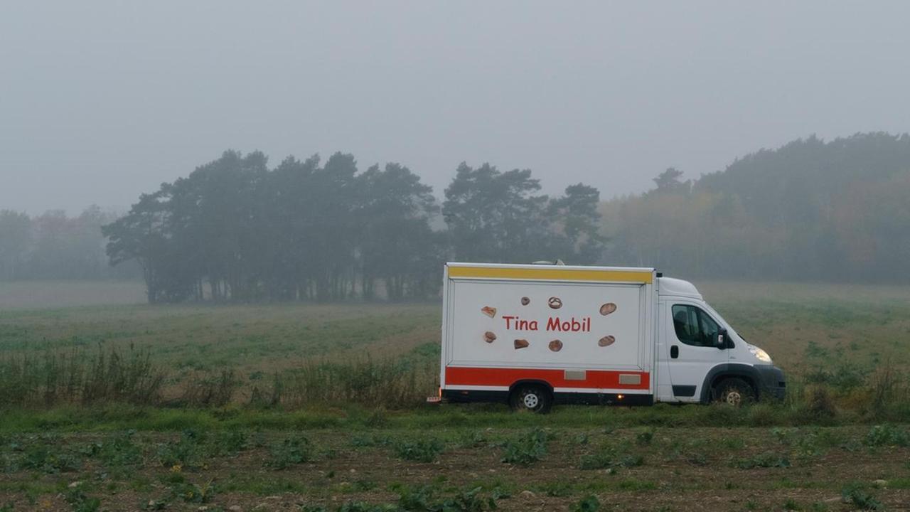Tinas Mobil fährt durchs Morgengrauen. An einer Haltestelle stehen Grundschüler und warten auf den Bus. Tinas Mobil fährt durchs Morgengrauen. An einer Haltestelle stehen Grundschüler und warten auf den Bus.