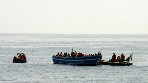 Bundeswehr-Soldaten auf einem kleinen Motorboot bergen im Mittelmeer Schiffbrüchige von einem Holzboot.