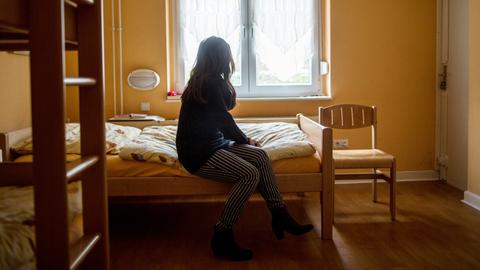 Eine Frau sitzt im Frauenhaus auf einem Bett, hier in Herne in Nordrhein-Westfalen.