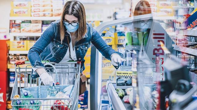 Eine Frau trägt eine Schutzmaske und Handschuhe bei ihrem Einkauf in einem Supermarkt während der Pandemie (aufgenommen in Kaprun am 4. April 2020)