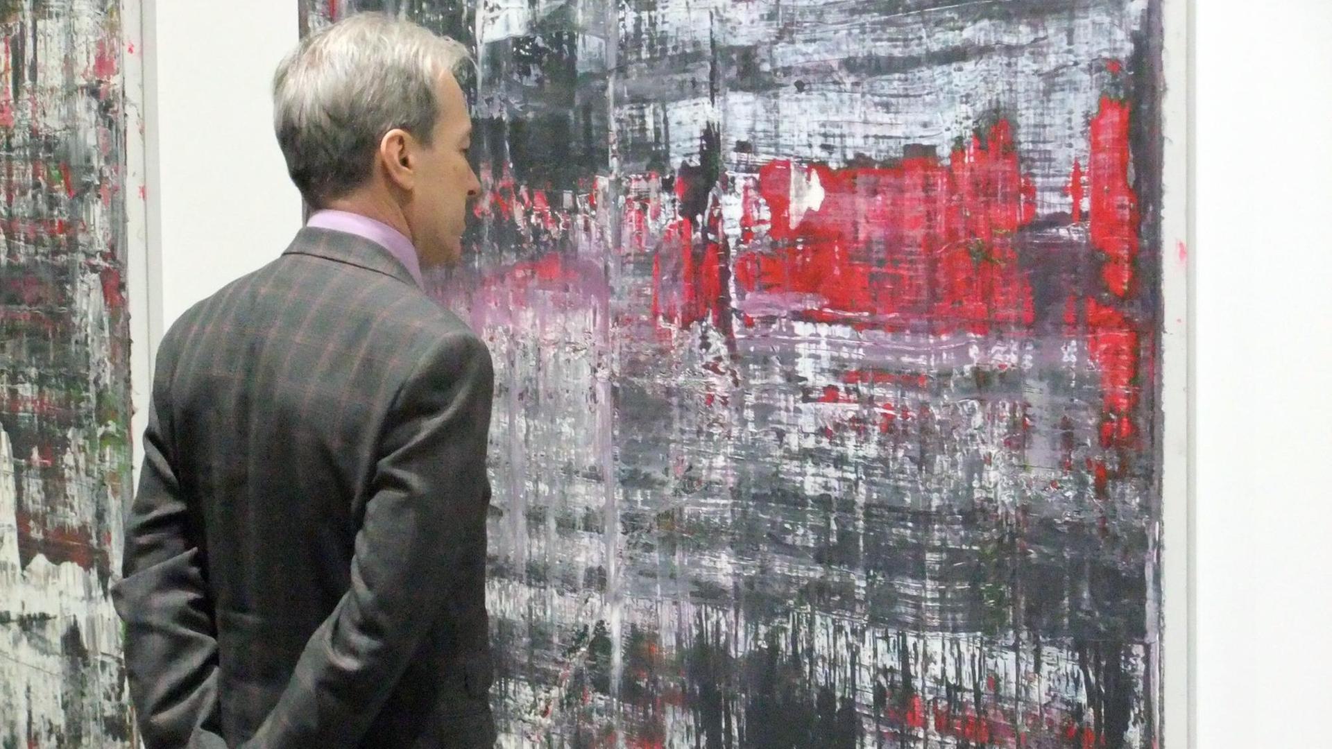 Ein Mann betrachtet das in schwarz, weiß und rot gehaltene Bild Ein Mann betrachtet das in schwarz, weiß und rot gehaltene Bild