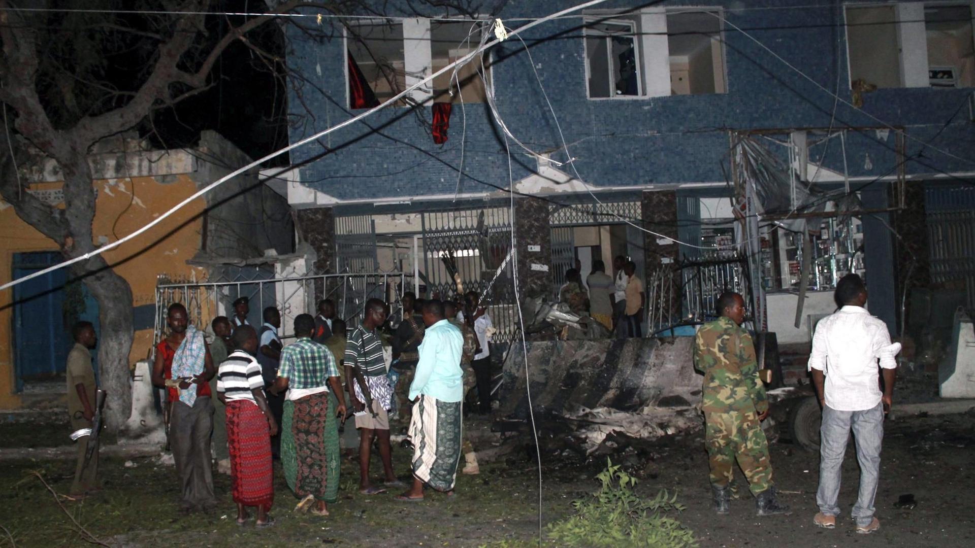 Residents and security officers gather at the scene of a car bomb explosion in front of a hotel that was attacked in Mogadishu, Somalia, 10 July 2015. Reports say the heavy gunfire followed explosions at Wehliya hotel in Mogadishu, killing at least 4 people. Somalia's Islamist militant group al-Shabab has claimed responsibility for the latest attack. EPA/SAID YUSUF WARSAME