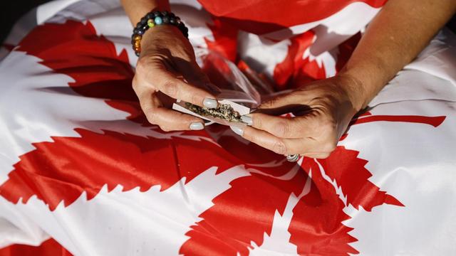Jemand baut einen Joint auf einer kanadischen Flagge.