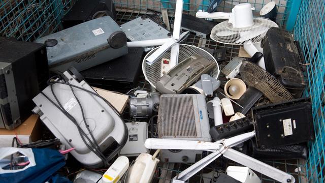 Man sieht alte Elektrogeräte auf einem Recyclinghof in einem Behälter für Elektroschrott.