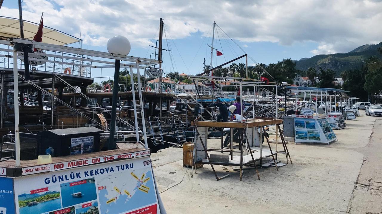 Am Hafen von Kas liegen zahlreiche große und kleine Schiffe vor Anker. Davor an Land die Verkaufsstände, die Ausflugstouren anbieten. Am Hafen von Kas liegen zahlreiche große und kleine Schiffe vor Anker. Davor an Land die Verkaufsstände, die Ausflugstouren anbieten.
