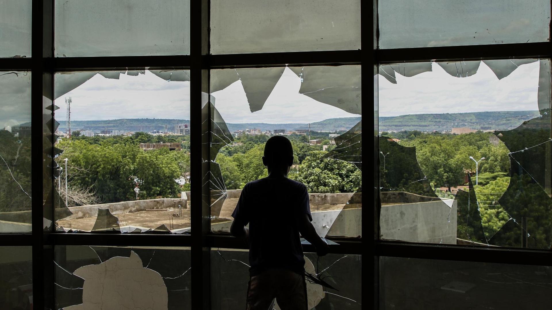 Ein Mensch schaut durch zerbrochene Fensterscheiben auf Malis Hauptstadt Bamako. Ein Mensch schaut durch zerbrochene Fensterscheiben auf Malis Hauptstadt Bamako.