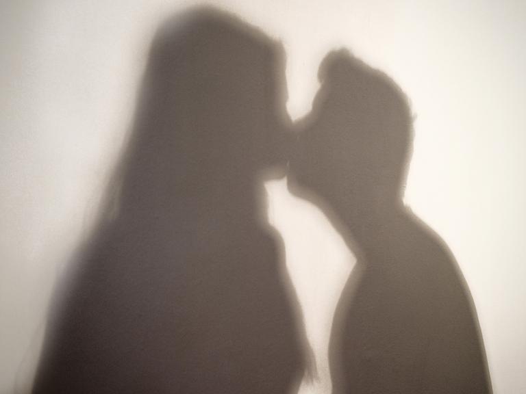 Der Schatten einer Frau und eines Mannes, die sich küssen.