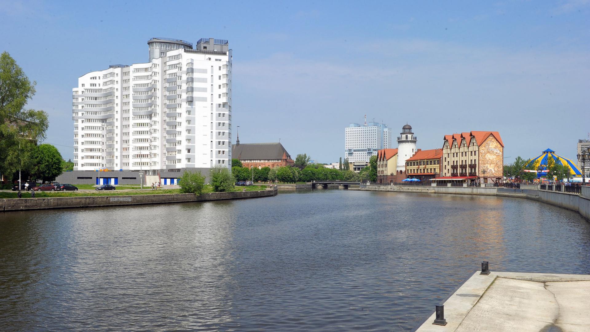 Hinter einer Wasserfläche ist ein großes Hochhaus und deneben ein kleines Ensemble historischer Gebäude zu sehen. Hinter einer Wasserfläche ist ein großes Hochhaus und deneben ein kleines Ensemble historischer Gebäude zu sehen.
