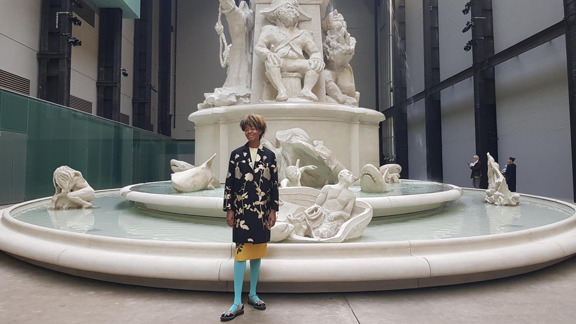 Die US-Künstlerin Kara Walker steht vor einem riesigen, mehrstufigen weißen Brunnen in der Londoner Tate Modern Galerie. Die US-Künstlerin Kara Walker steht vor einem riesigen, mehrstufigen weißen Brunnen in der Londoner Tate Modern Galerie.