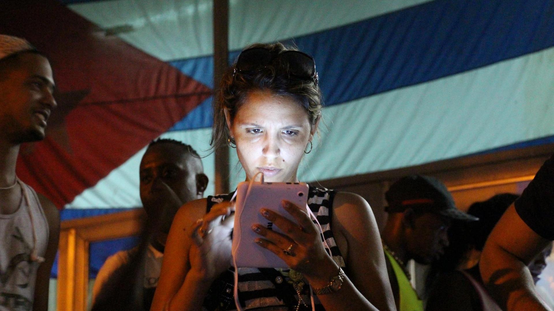 Eine junge Frau surft am 16.10.2015 an einem öffentlichen WLAN-Spot im Stadtbezirk Marianao, Havanna, Kuba, im Internet. Öffentliche WLAN-Spots sorgen für Begeisterung bei jungen Menschen in Havanna. Mit einem begrenzten Angebot wollen die Castros die vormals isolierte Insel behutsam in die Online-Welt führen. Foto: Isaac Risco/dpa (zu dpa «Das sozialistische Kuba öffnet das Internet für seine Bürger» vom 22.10.2015) | Verwendung weltweit