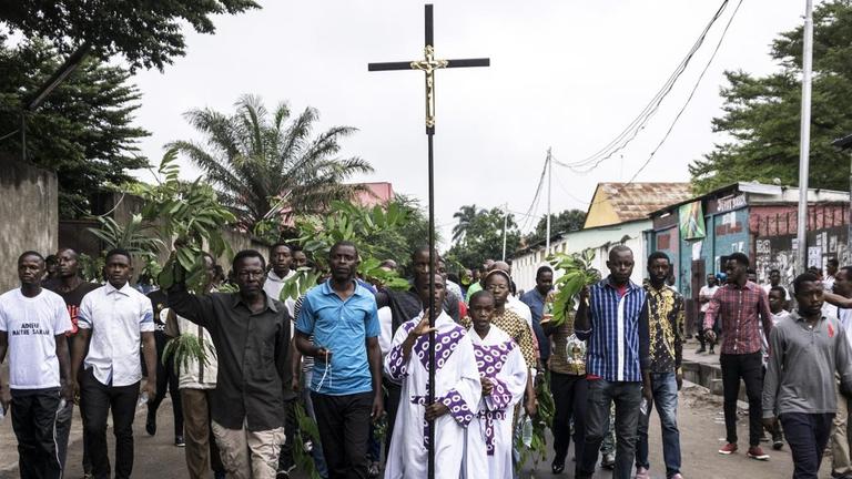 Kirchennahe Demonstranten in der Demokratischen Republik Kongo protestieren gegen Präsident Kabila. Ein Mann in der Mitte der Gruppe trägt ein großes Kreuz. Kirchennahe Demonstranten in der Demokratischen Republik Kongo protestieren gegen Präsident Kabila. Ein Mann in der Mitte der Gruppe trägt ein großes Kreuz.