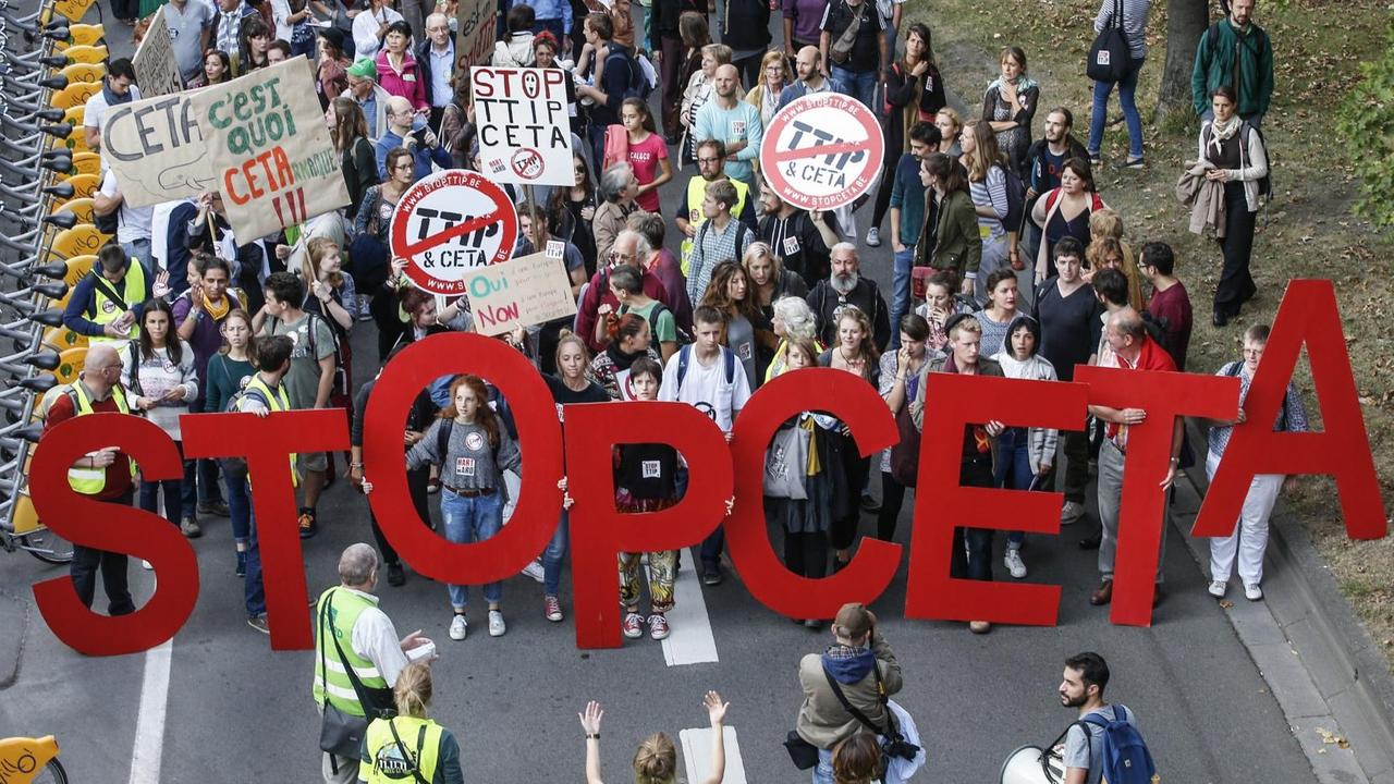 Die Demonstranten laufen eine Straße entlang und tragen die Buchstaben "Stop Ceta". Die Demonstranten laufen eine Straße entlang und tragen die Buchstaben "Stop Ceta".