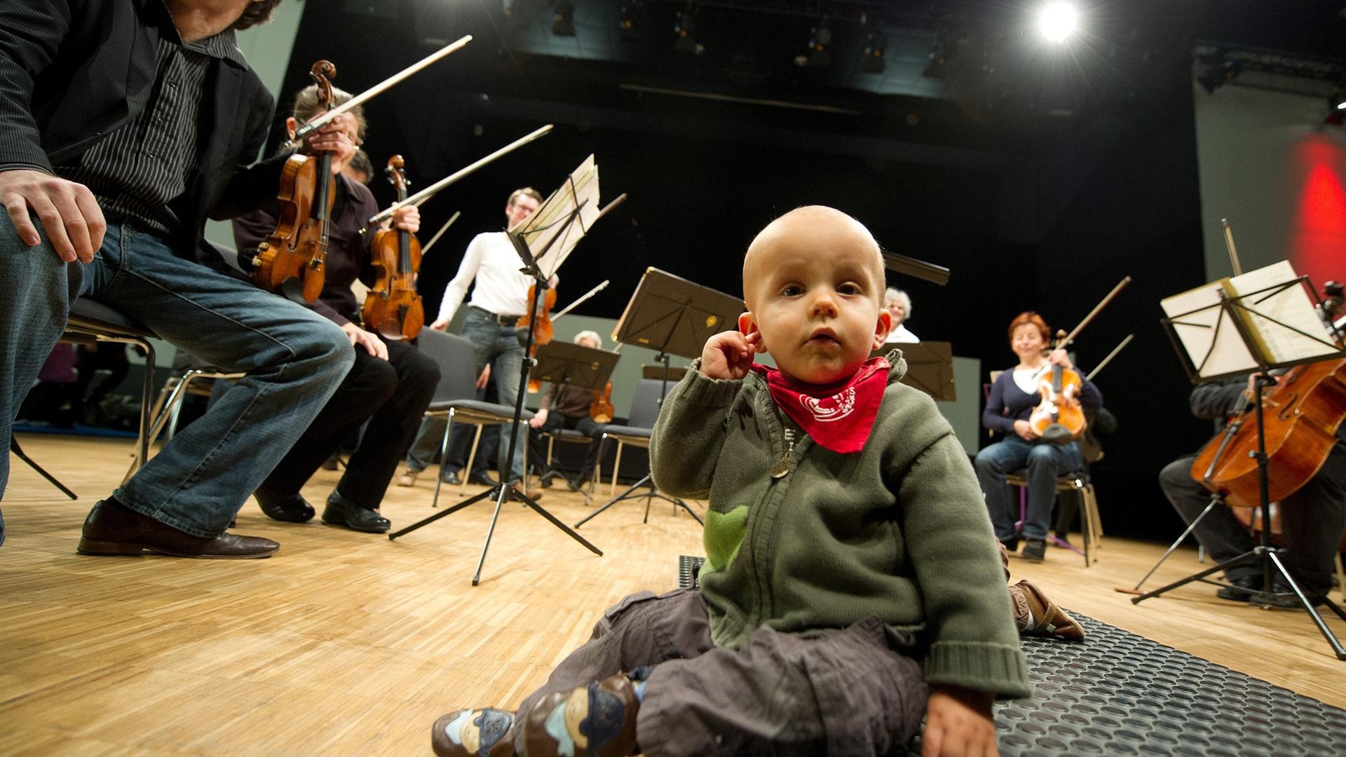 Der kleine Niklas fasst sich am 21.11.2012 in Heilbronn (Baden-Württemberg) vor Beginn des Babykonzerts des Württembergischen Kammerorchesters Heilbronn an sein Ohr. Eltern mit ihren Babys besuchten das ausverkaufte Konzert des Orchesters, das klassische Musik spielte.