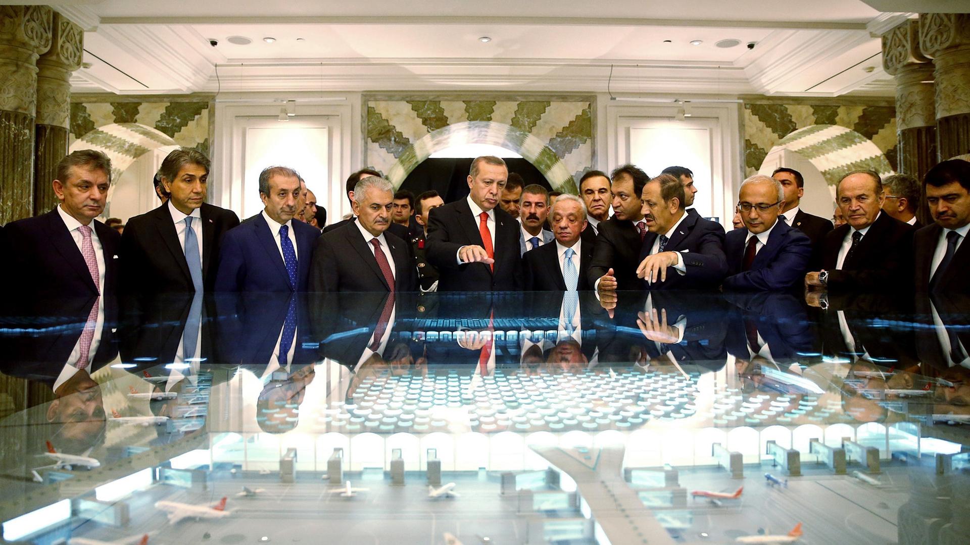 Der türkische Präsident Recep Tayyip Erdogan steht in einer Gruppe von Männern bei der Unterschriften-Zeremonie der "Istanbul New Airport Project Financing" am 19.10.2015 in Istanbul vor einem großen Modell des Flughafens. Der türkische Präsident Recep Tayyip Erdogan steht in einer Gruppe von Männern bei der Unterschriften-Zeremonie der "Istanbul New Airport Project Financing" am 19.10.2015 in Istanbul vor einem großen Modell des Flughafens.