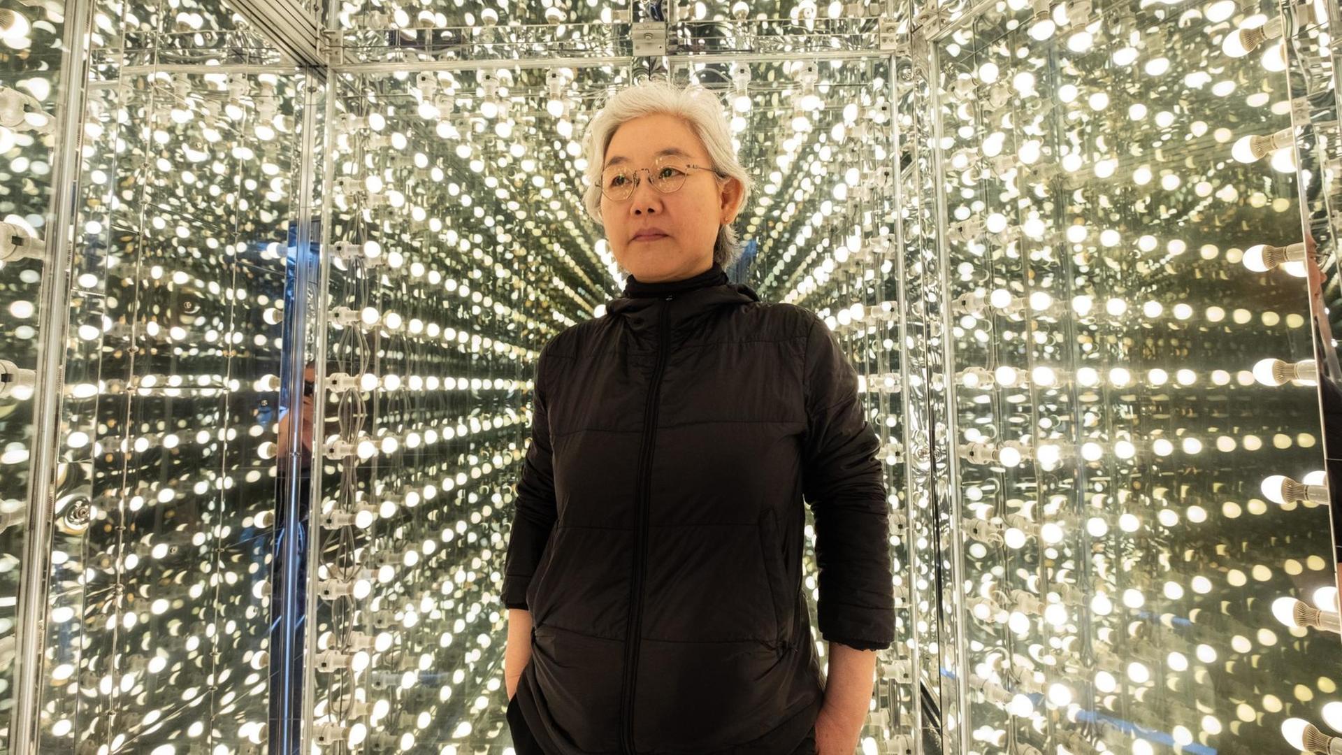 Lee Bul steht im schwarzen Rollkragenpullover vor ihrer Lichtinstallation Via Negative II. Lee Bul steht im schwarzen Rollkragenpullover vor ihrer Lichtinstallation Via Negative II.
