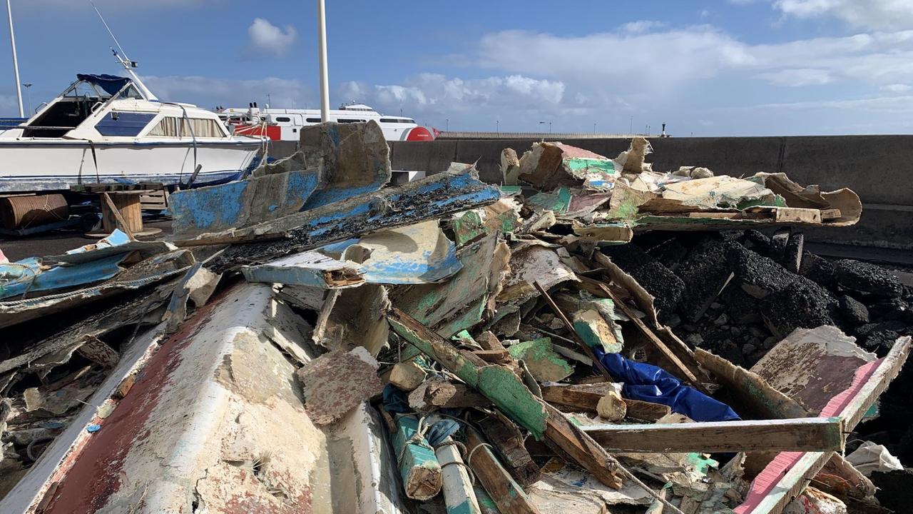 Bunt angemalte Holzreste, kaum als ehemaliges Boot zu erkennen, liegen im Hafen auf dem Boden herum. Bunt angemalte Holzreste, kaum als ehemaliges Boot zu erkennen, liegen im Hafen auf dem Boden herum.