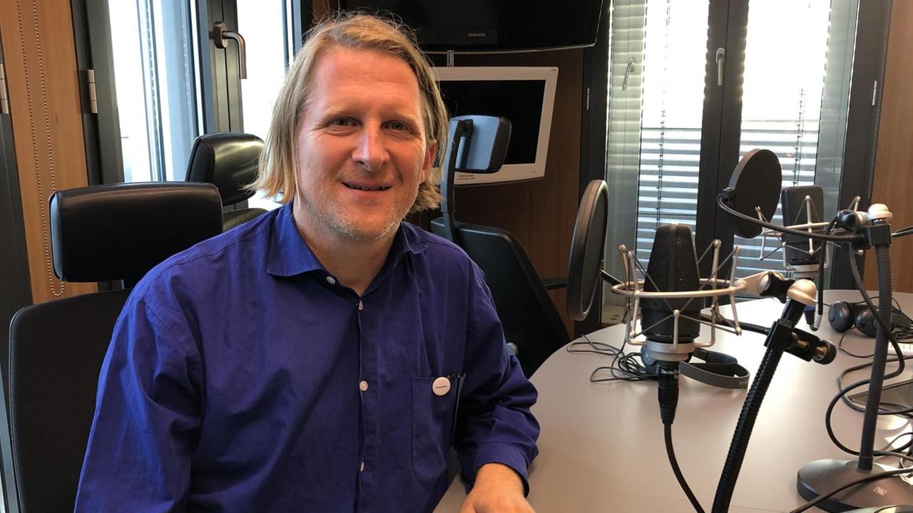 Björn Kunter sitzt im Radiostudio vor einem Mikrophone.