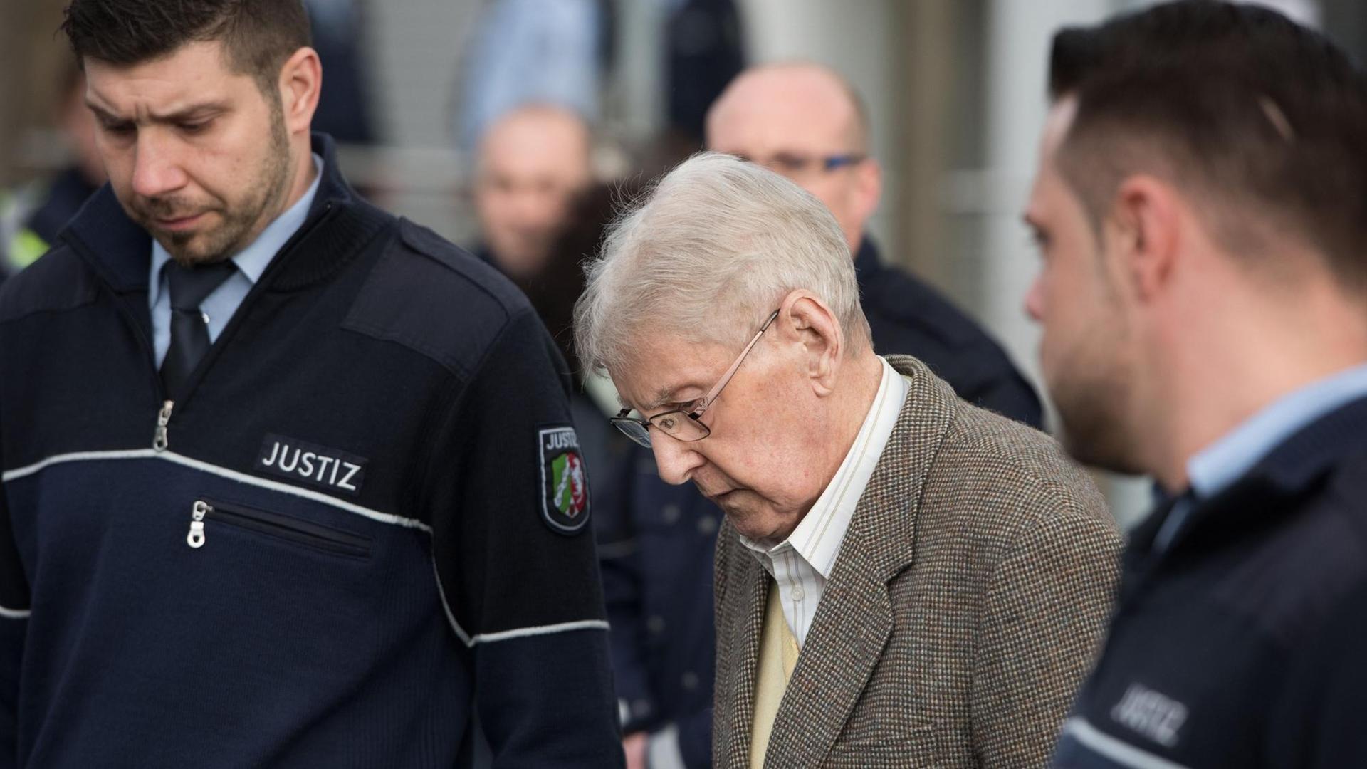 Der frühere Auschwitz-Wachmann Reinhold Hanning (M) wird am 11.02.2016 in Detmold (Nordrhein-Westfalen) nach dem Ende des ersten Prozesstages aus dem Gebäude begleitet. Dem 94-Jährigen wird Beihilfe zum Mord in mindestens 170 000 Fällen vorgeworfen. Der Prozess vor dem Landgericht Detmold findet in den Räumen der Industrie und Handelskammer IHK statt. Foto: Bernd Thissen/dpa Der frühere Auschwitz-Wachmann Reinhold Hanning (M) wird am 11.02.2016 in Detmold (Nordrhein-Westfalen) nach dem Ende des ersten Prozesstages aus dem Gebäude begleitet. Dem 94-Jährigen wird Beihilfe zum Mord in mindestens 170 000 Fällen vorgeworfen. Der Prozess vor dem Landgericht Detmold findet in den Räumen der Industrie und Handelskammer IHK statt. Foto: Bernd Thissen/dpa