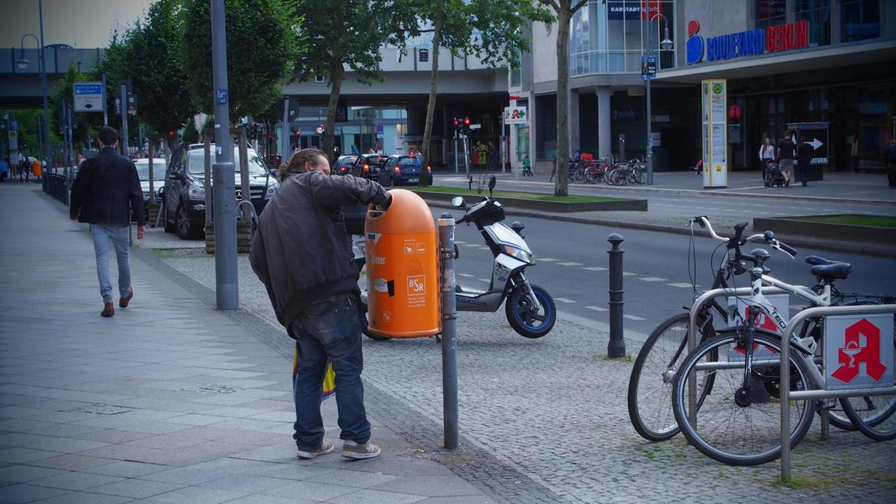 Ein Mann greift im auf der Schloßstraße im Bezirk Steglitz/Zehlendorf in Berlin am 15.06.2014 in einen Papierkorb, um an eine Pfandflasche zu kommen. Ein Mann greift im auf der Schloßstraße im Bezirk Steglitz/Zehlendorf in Berlin am 15.06.2014 in einen Papierkorb, um an eine Pfandflasche zu kommen.