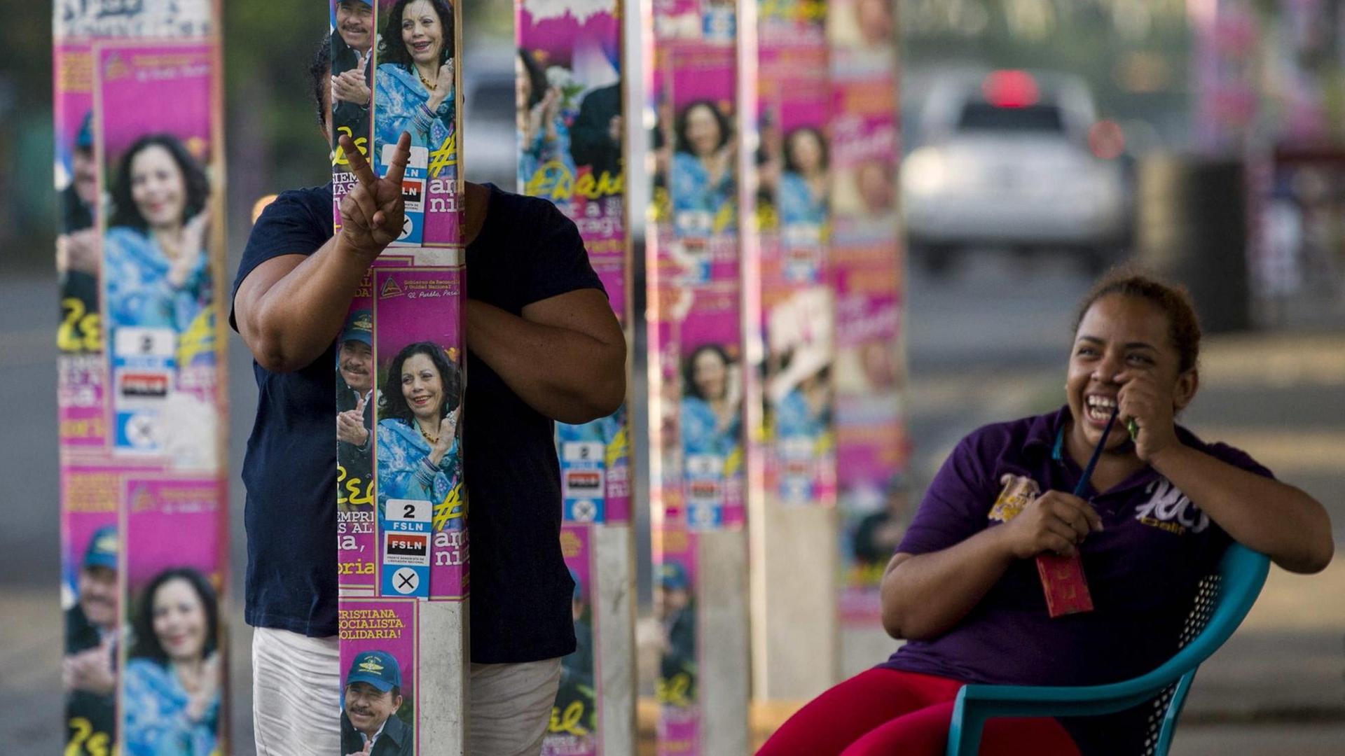 Eine lachende Frau versteckt sich hinter Wahlwerbung in Nicaragua. Eine lachende Frau versteckt sich hinter Wahlwerbung in Nicaragua.