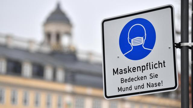 Ein Schild weist auf die Maskenpflicht in der Innenstadt hin