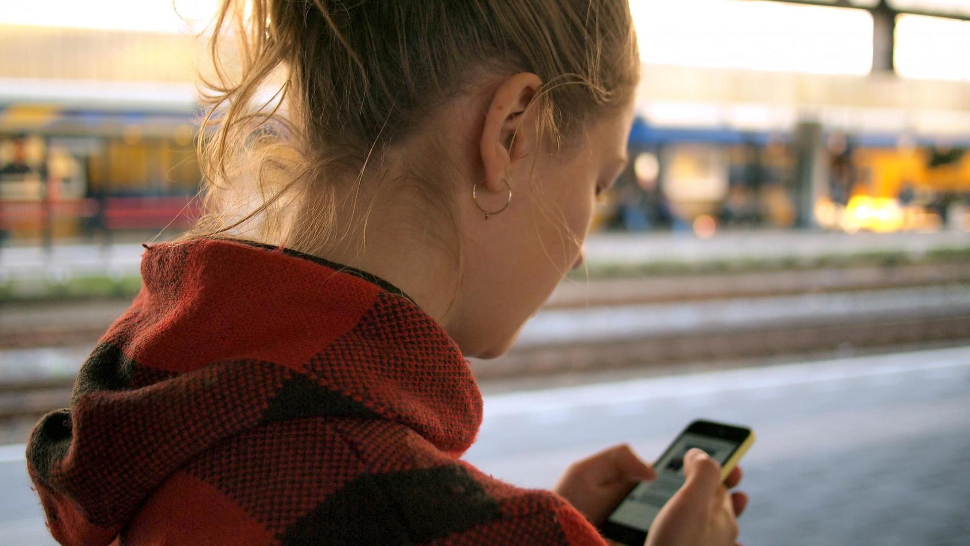 Eine junge Frau schaut auf ihr Smartphone. Eine junge Frau schaut auf ihr Smartphone.