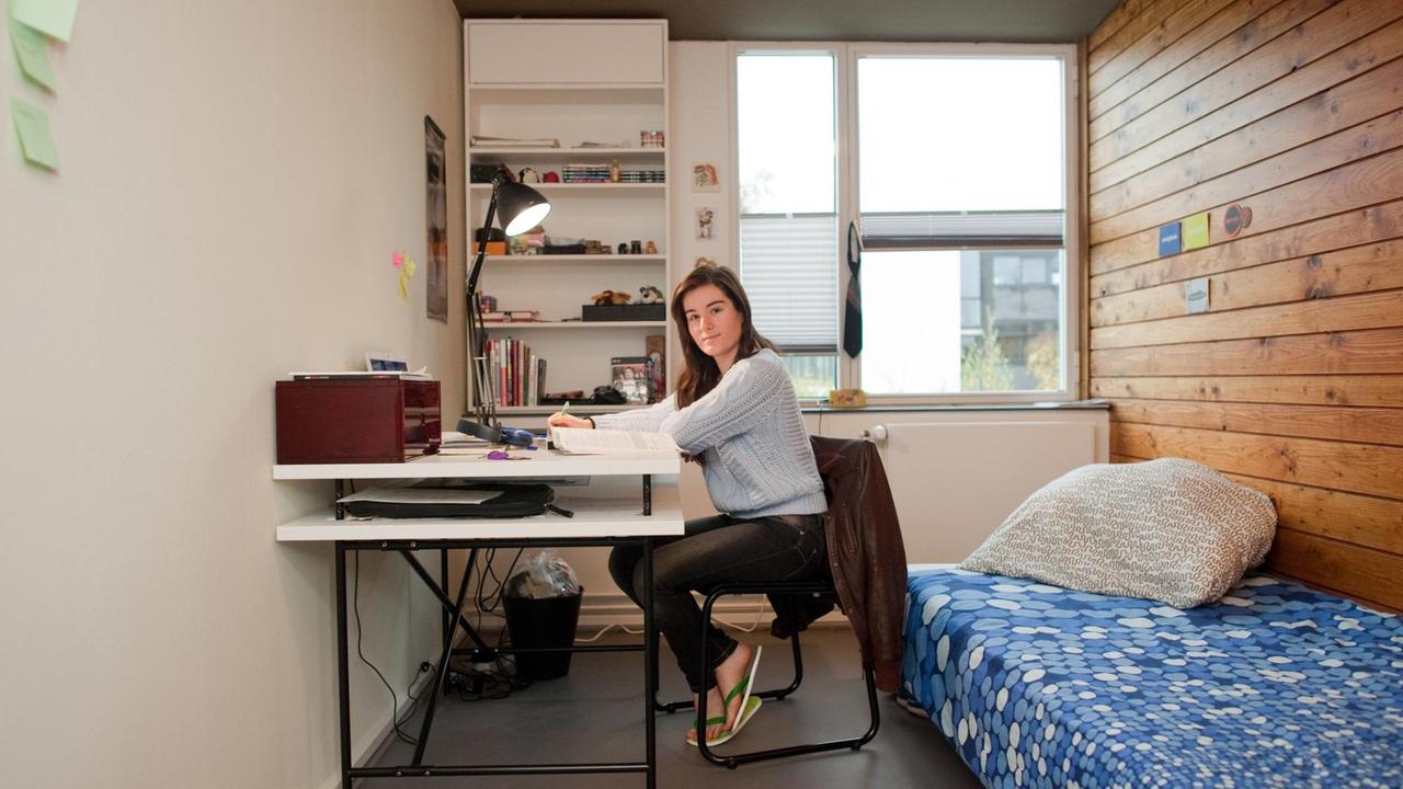 Eine junge Frau sitzt an einem Schreibtisch in einem kleinen Zimmer im Studentendorf Schlachtensee.
