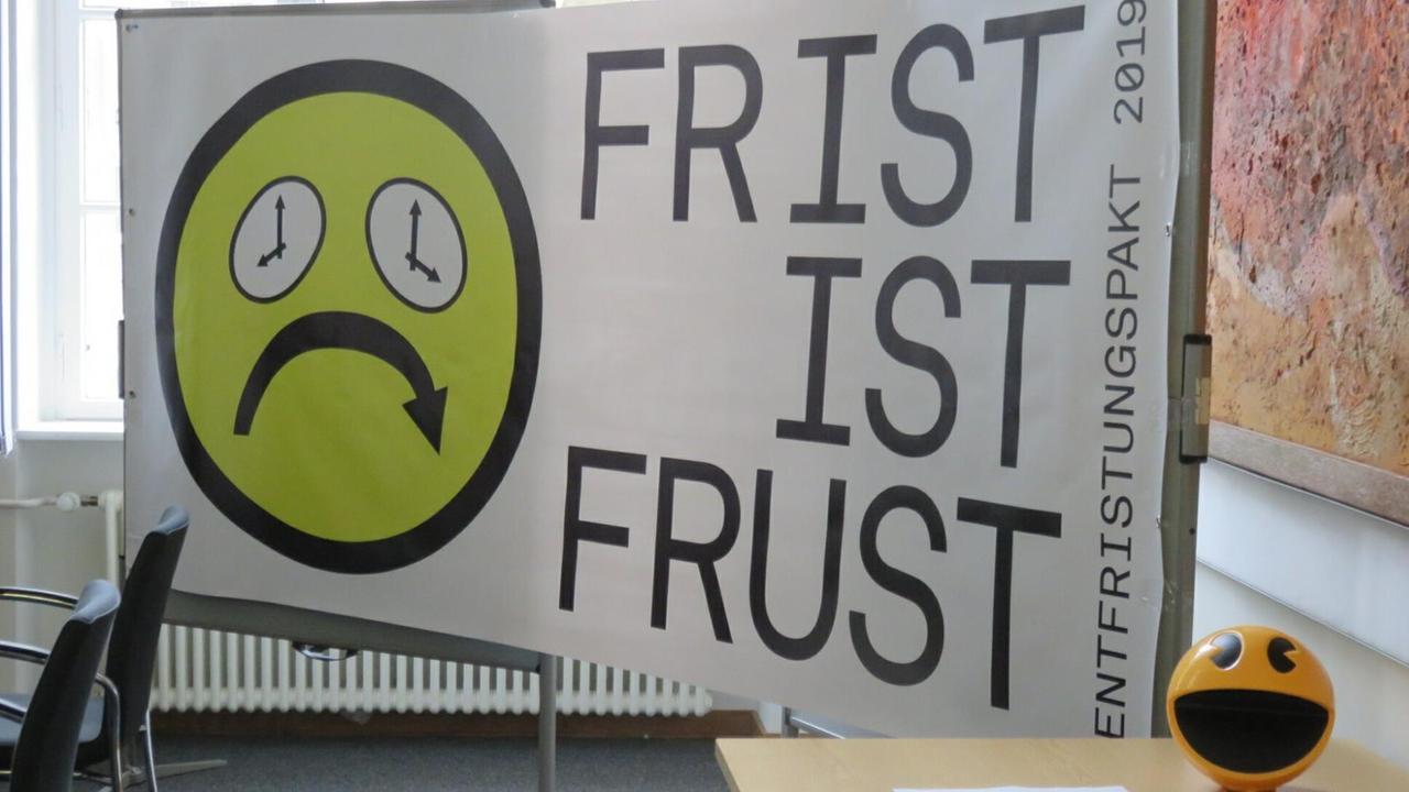 Ein trauriger Smiley mit Augen aus tickenden Uhren. Daneben steht der Schriftzug "Frist ist Frust" Ein trauriger Smiley mit Augen aus tickenden Uhren. Daneben steht der Schriftzug "Frist ist Frust"