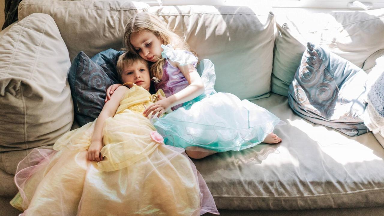 Ein Mädchen und ein Junge, beide in Kleidern, sitzen zusammen auf der Couch. Ein Mädchen und ein Junge, beide in Kleidern, sitzen zusammen auf der Couch.