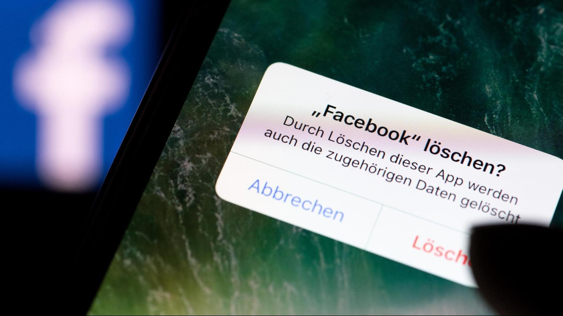 Auf dem Bildschirm eines Smartphones steht vor dem Logo der Facebook-App der Dialog "Facebook löschen?" Auf dem Bildschirm eines Smartphones steht vor dem Logo der Facebook-App der Dialog "Facebook löschen?"