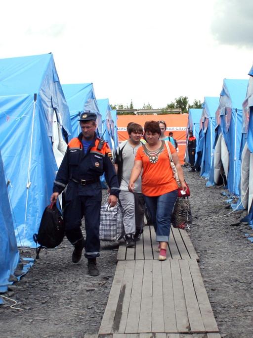 Neuankömmlinge aus dem Konfliktgebiet Ostukraine werden am 09.07.2014 von russischen Helfern im Flüchtlingslager in Nowoschachtinsk zu Zelten gebracht.