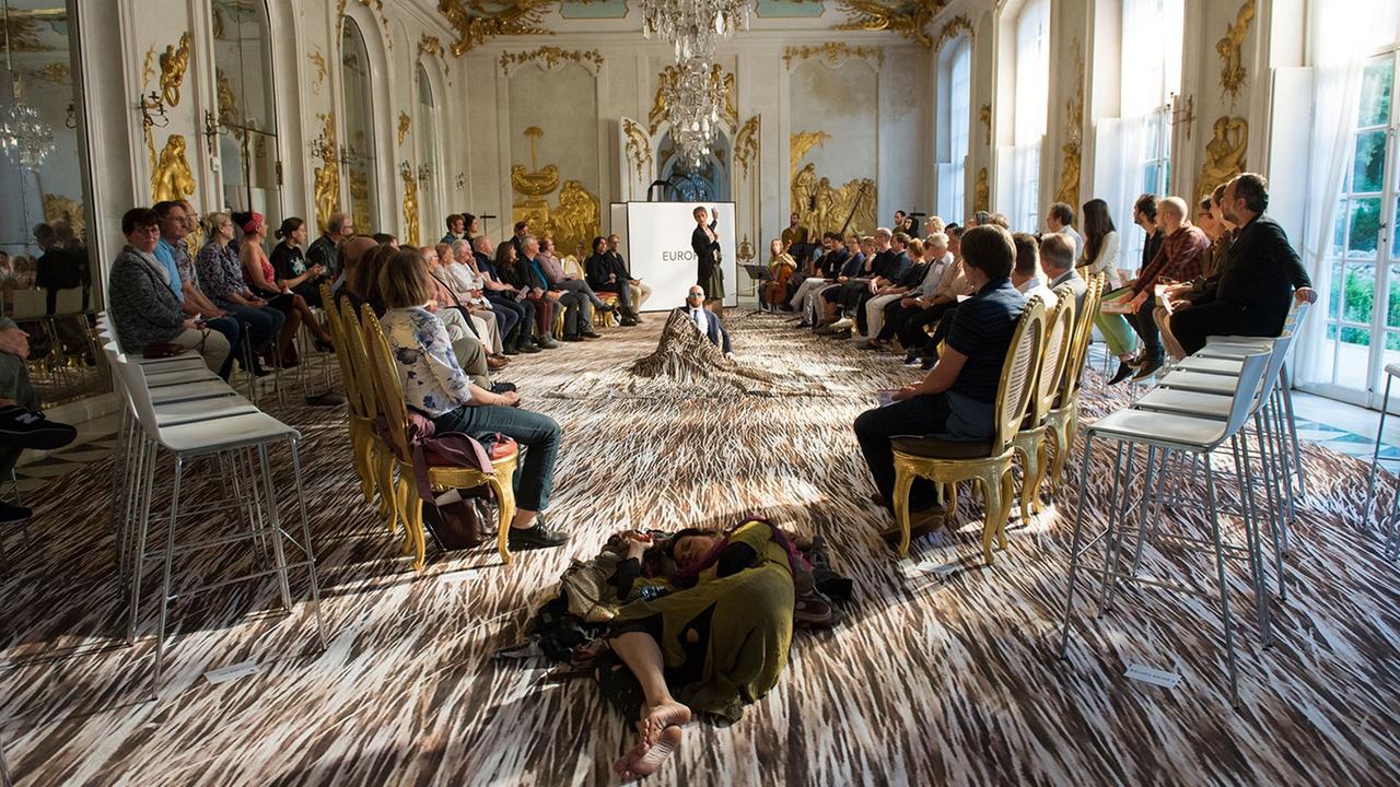 In einem barocken Saal im Potsdamer Orangerieschloss sitzen die Zuschauer um die Sänger In einem barocken Saal im Potsdamer Orangerieschloss sitzen die Zuschauer um die Sänger