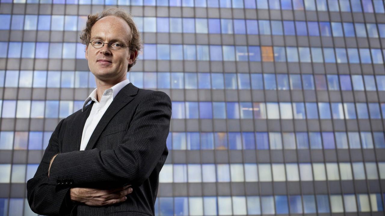 Der Wirtschaftswissenschaftler und Journalist Prof. Dr. Sebastian Dullien posiert für ein Foto vor dem Postbank-Hochhaus in Berlin-Kreuzberg.