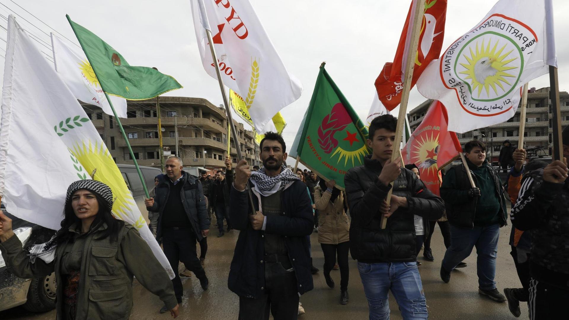 Syrische-kurdische Demonstranten schwenken Fahnen während einer Demonstration im Nordosten Syriens.