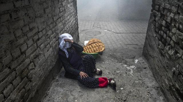 Eine Frau in der Stadt Diyarkir (Türkei), die ihr Gesicht schützt, während sich türkische Polizisten und PKK-Anhänger Gefechte mit Tränengas liefern.
