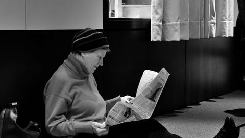 Die Schauspielerin Uta Hallant liest am Boden sitzend in einer Zeitung.