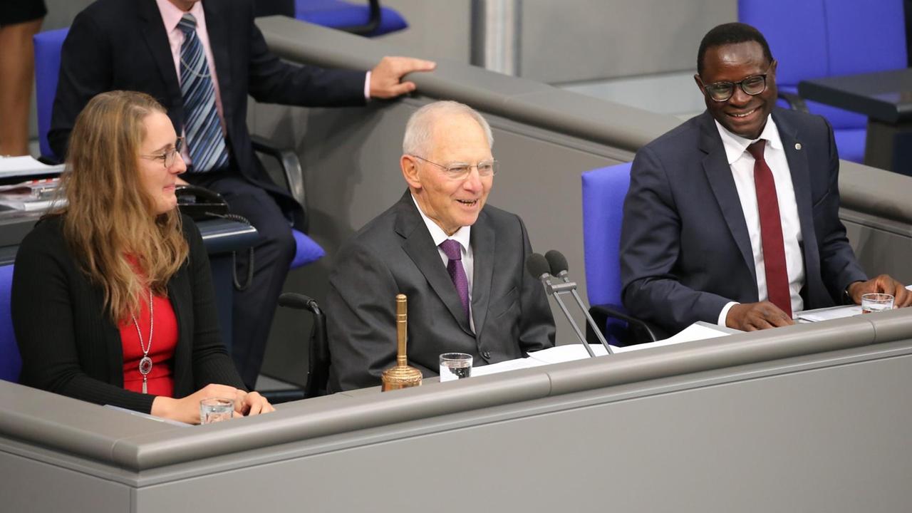 Schäuble lächelt ins Plenum, links von ihm und hinter ihm zwei weitere Personen. Schäuble lächelt ins Plenum, links von ihm und hinter ihm zwei weitere Personen.