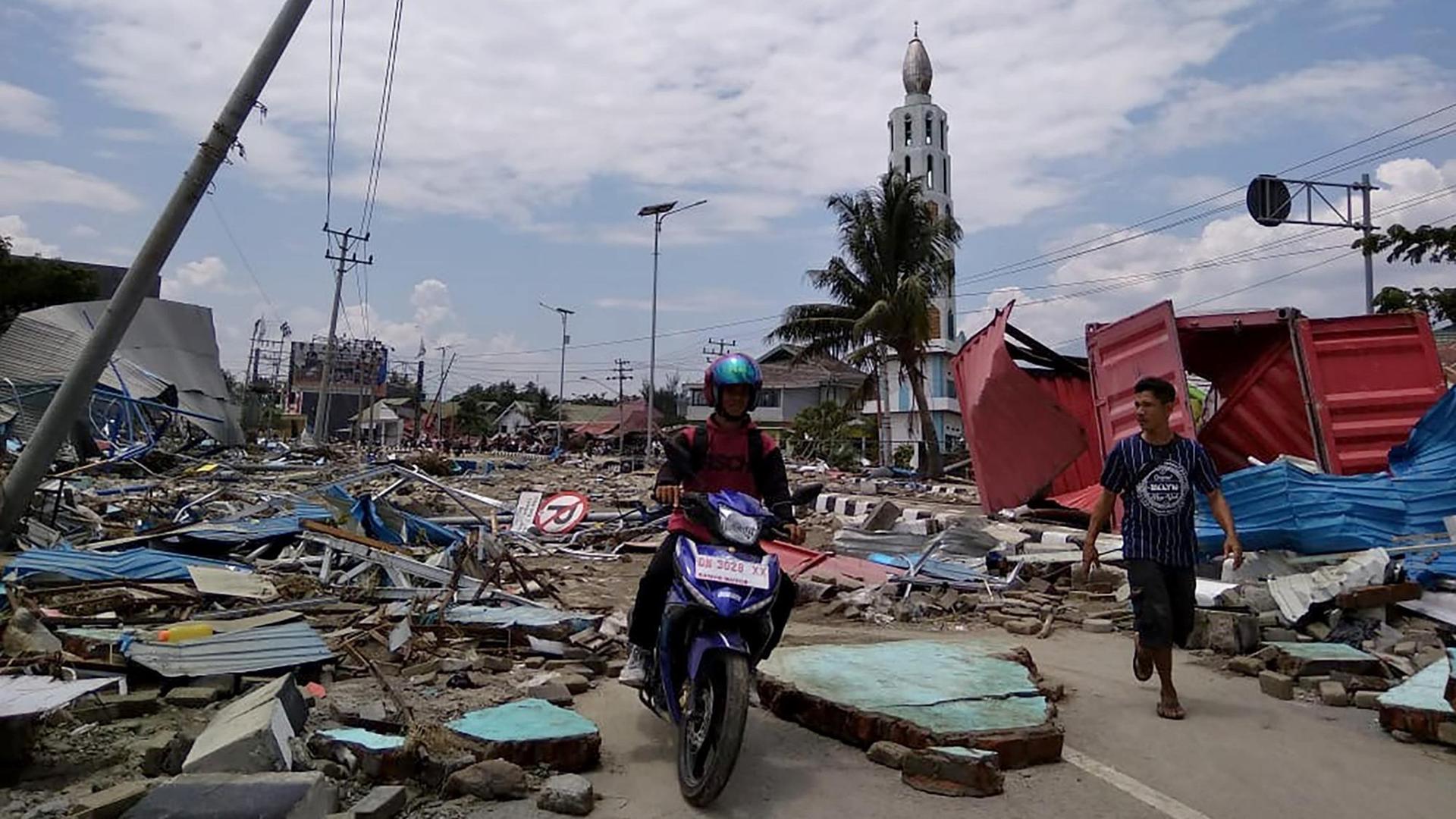 Pejalan kaki dan sepeda motor melewati jalan rusak di Indonesia.