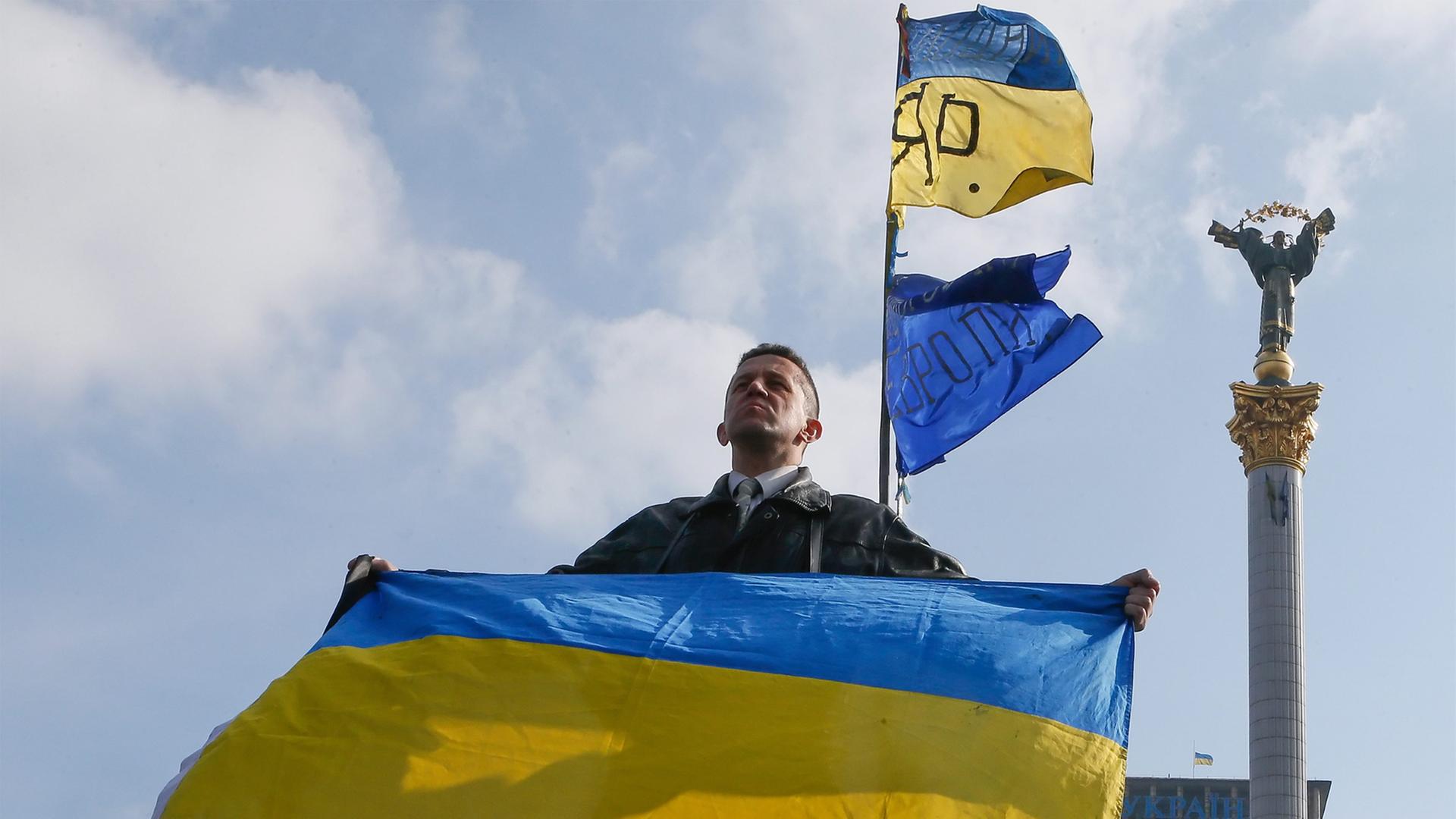 Ein Ukrainer hält in Kiew die Nationalflagge in die Höhe. Ein Ukrainer hält in Kiew die Nationalflagge in die Höhe.