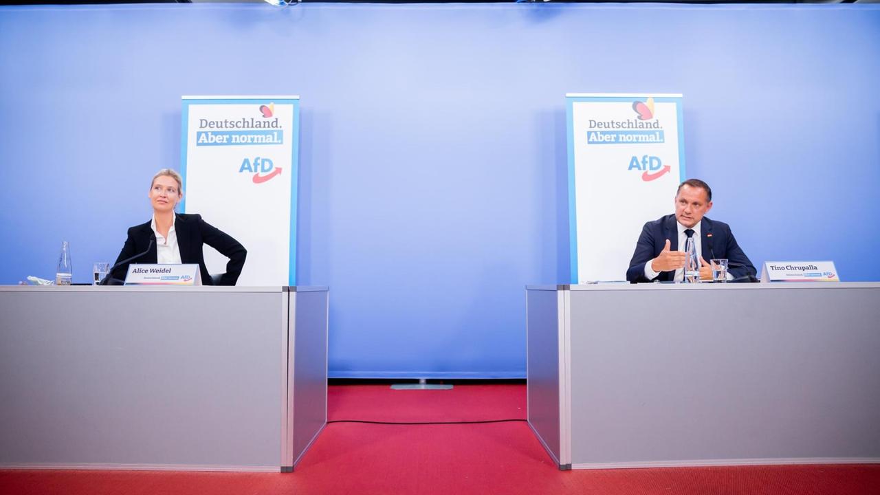 Die AfD-Spitzenkandidaten Alice Weidel (l) und Tino Chrupalla (r) bei der Vorstellung ihrer Kampagne zur Bundestagswahl in Berlin. Sie sitzen in großem Abstand zueinander auf einem Podium. An der Wand Plakate mit der Aufschrift "Deutschland. Aber normal". Die AfD-Spitzenkandidaten Alice Weidel (l) und Tino Chrupalla (r) bei der Vorstellung ihrer Kampagne zur Bundestagswahl in Berlin. Sie sitzen in großem Abstand zueinander auf einem Podium. An der Wand Plakate mit der Aufschrift "Deutschland. Aber normal".