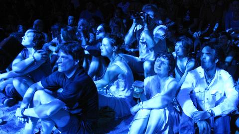 In blaues Licht getaucht blicken Besucher des TFF Rudolstadt Richtung Bühne.