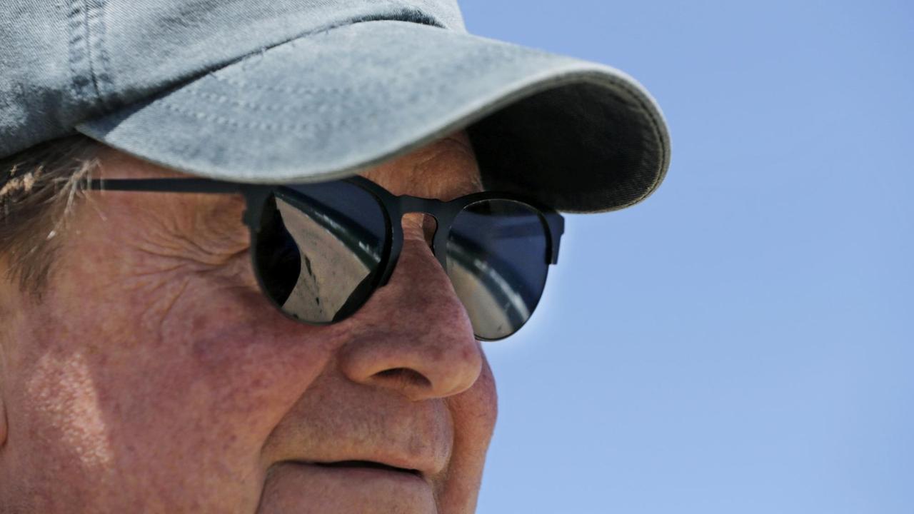 Ein Mann mit Cappy blickt auf den Strand, der sich in seinen Sonnenbrillengläsern spiegelt. Ein Mann mit Cappy blickt auf den Strand, der sich in seinen Sonnenbrillengläsern spiegelt.