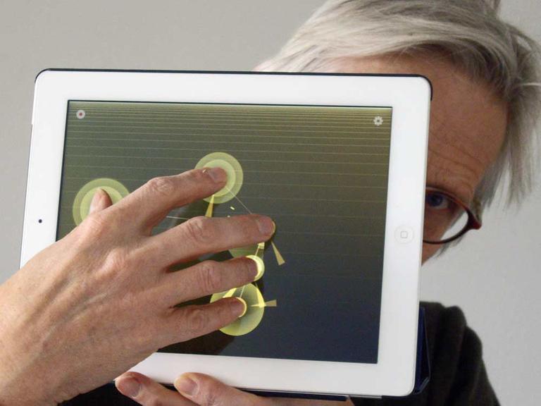 Maximilian Schönherr hält den Bildschirm seines Tablet-Computers in die Kamera und zeigt, wie man die Musiksoftware benutzt.
